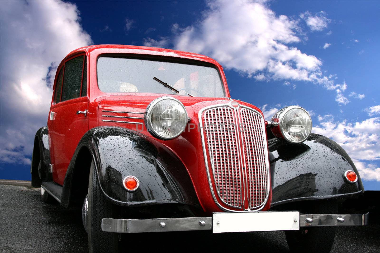 Vintage red luxury car and the blue sky. Droplets of rain.