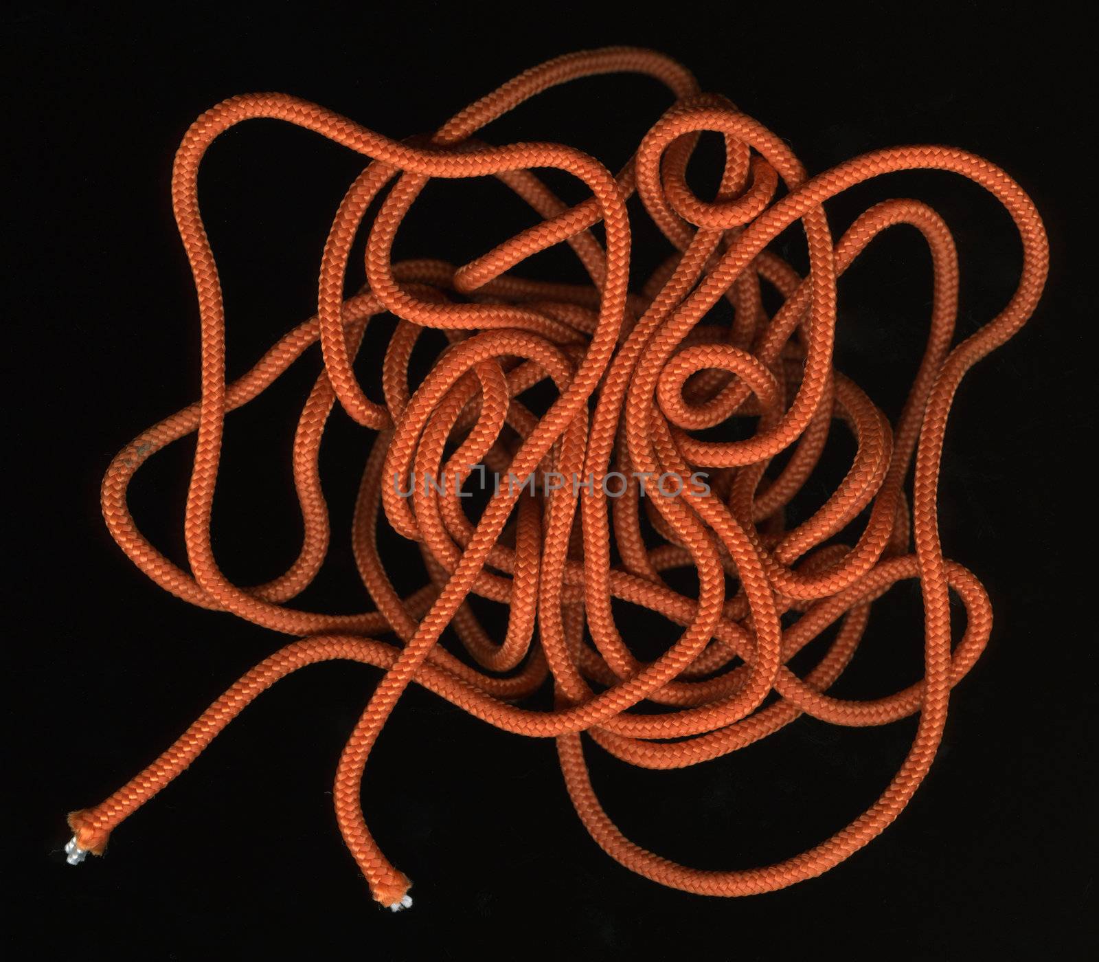 loose, random coils of orange, nylon cord against black background
