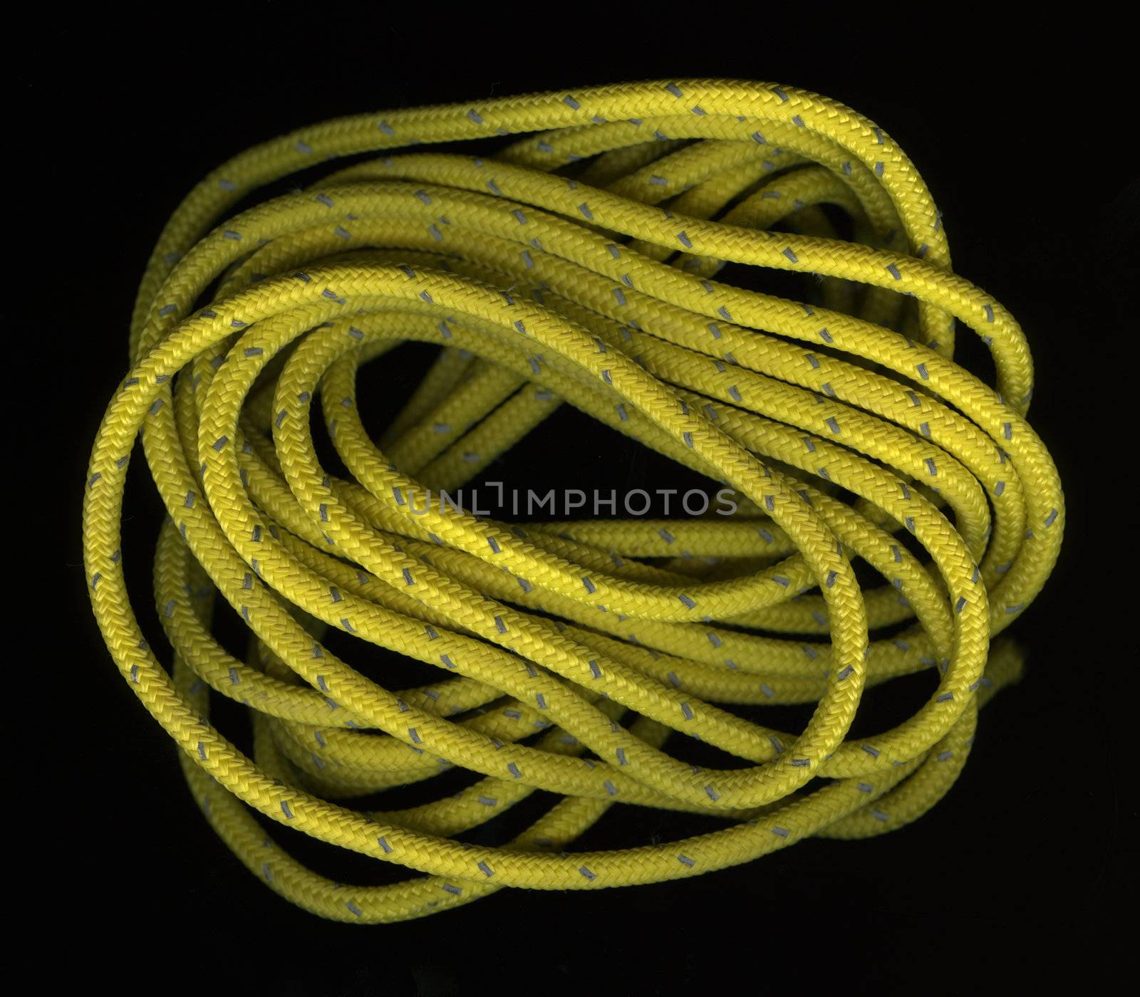 loose coils of yellow, nylon rope wit a reflective, silver thread on black background
