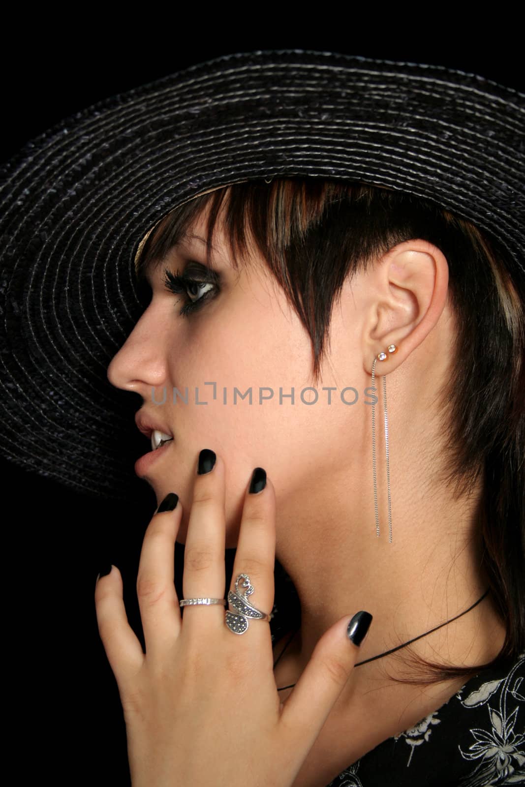 The young beautiful girl in a straw hat, on a black background