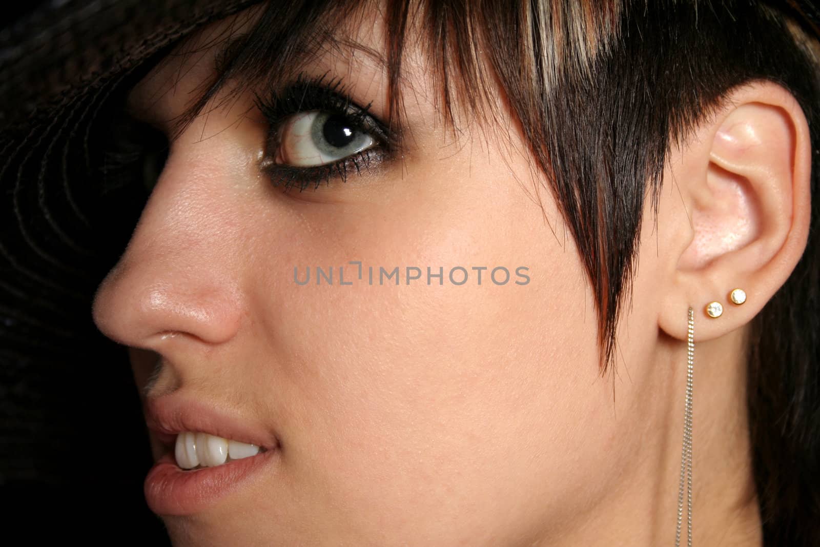 The young beautiful girl in a hat, on a black background