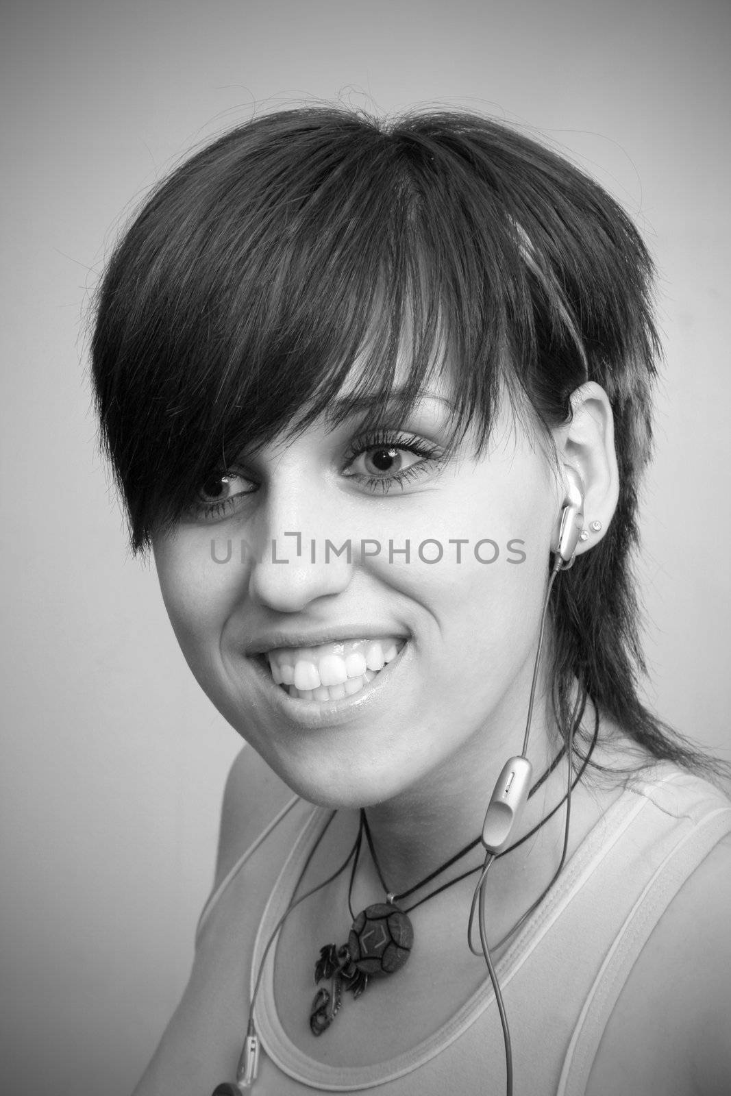 A smiling young girl with mobile's headphones, isolated on white