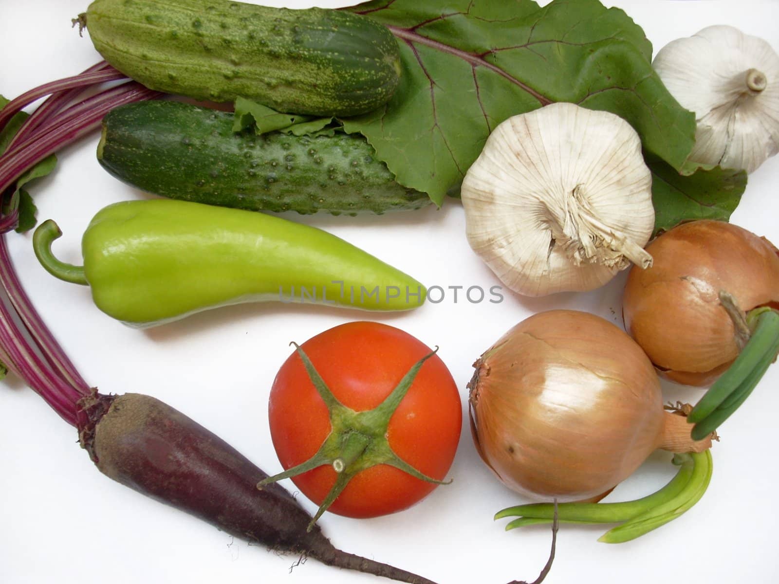This is a photograph of some fresh and sweet vegetables: tomatoes, cucumbers, onions, garlic, peppers, radish. 