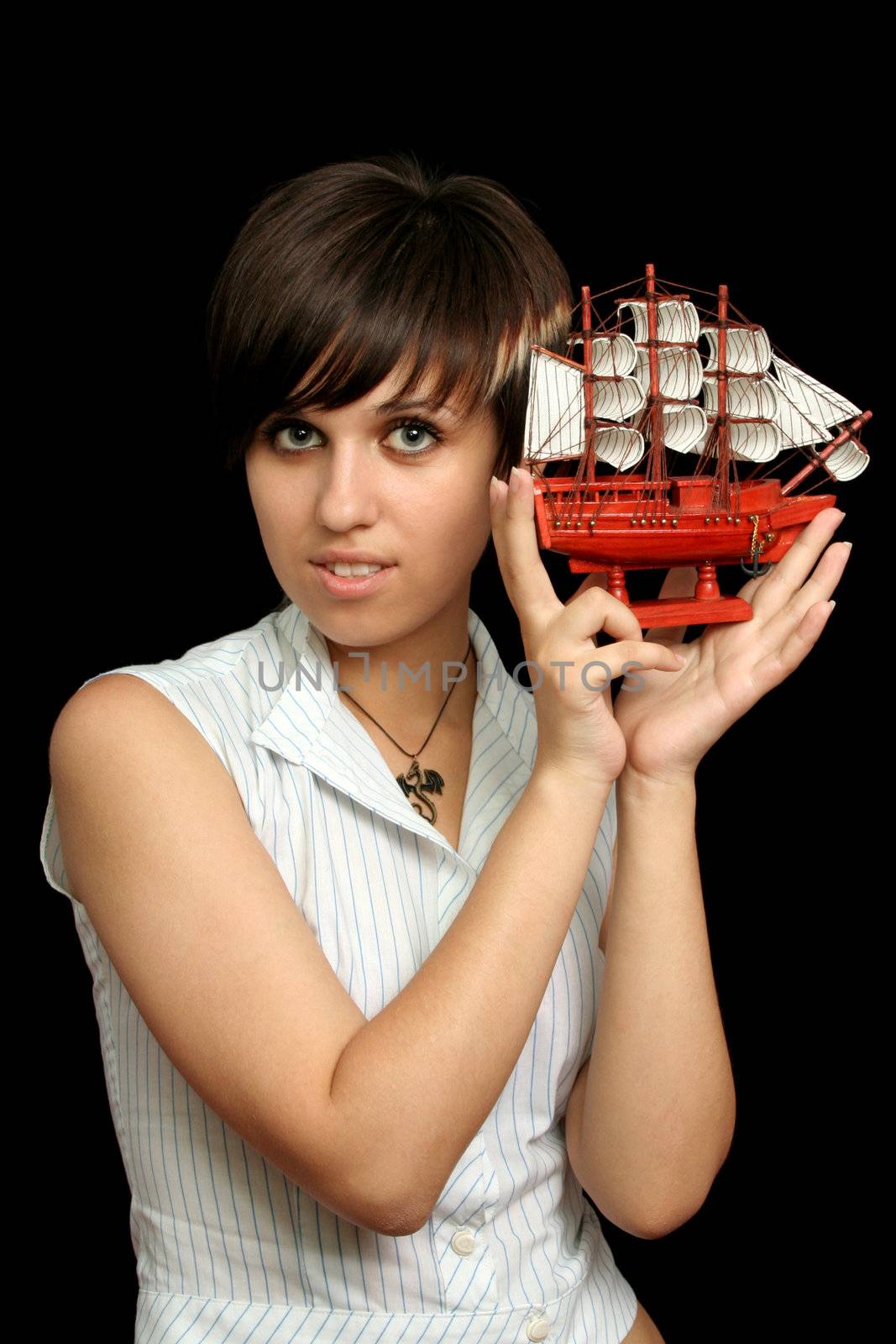 The nice girl with the toy ship in a hand, isolated on black background