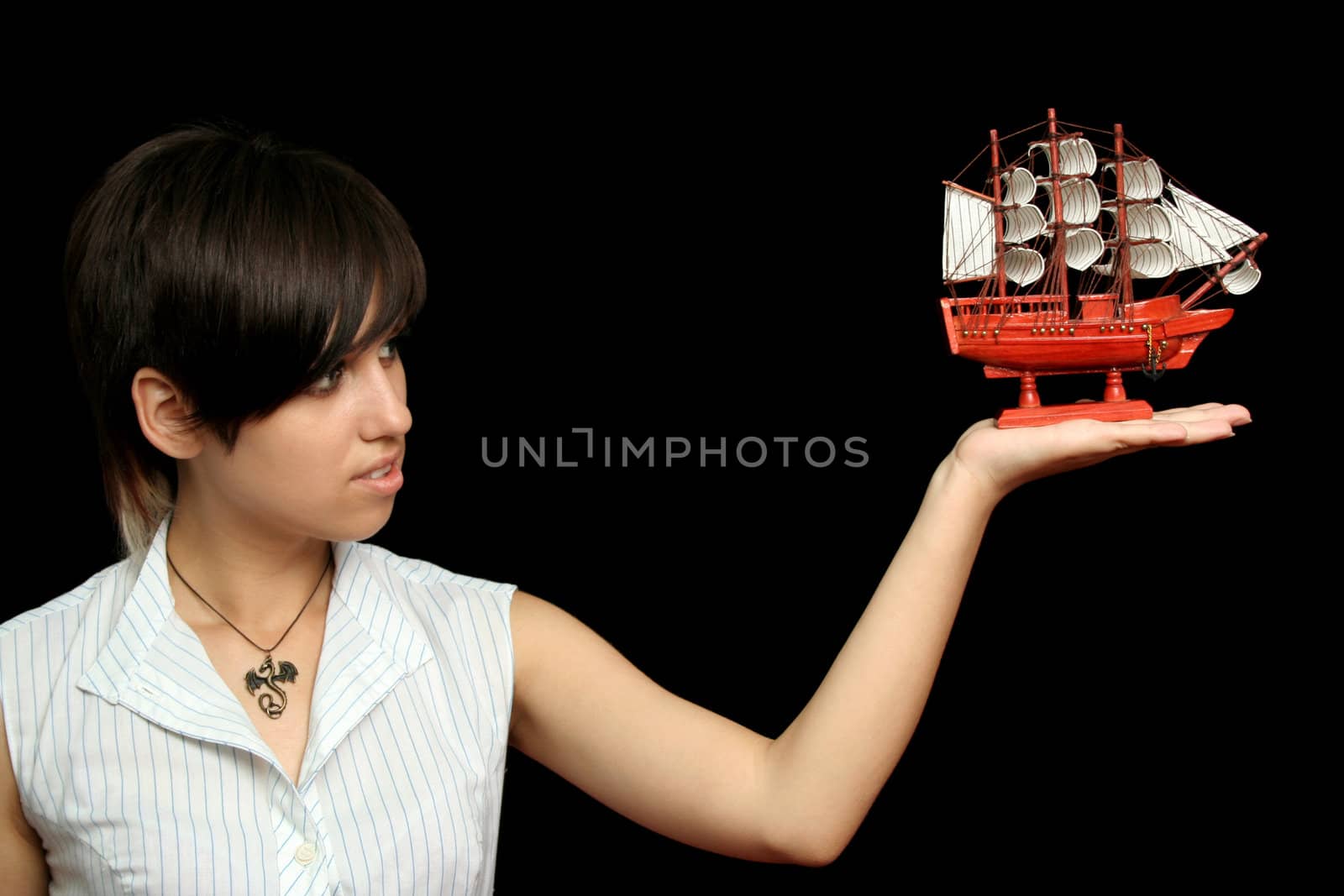 The nice girl with the toy ship in a hand, isolated on black background