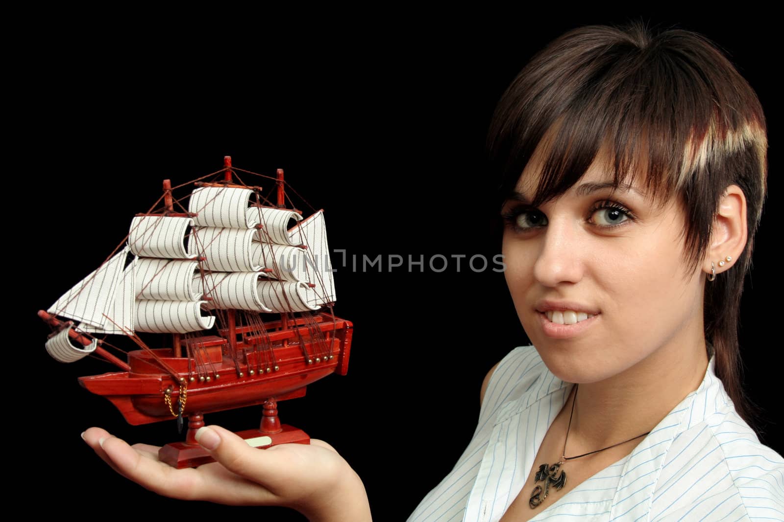 The nice smiling girl with the toy ship in a hand, isolated on black background