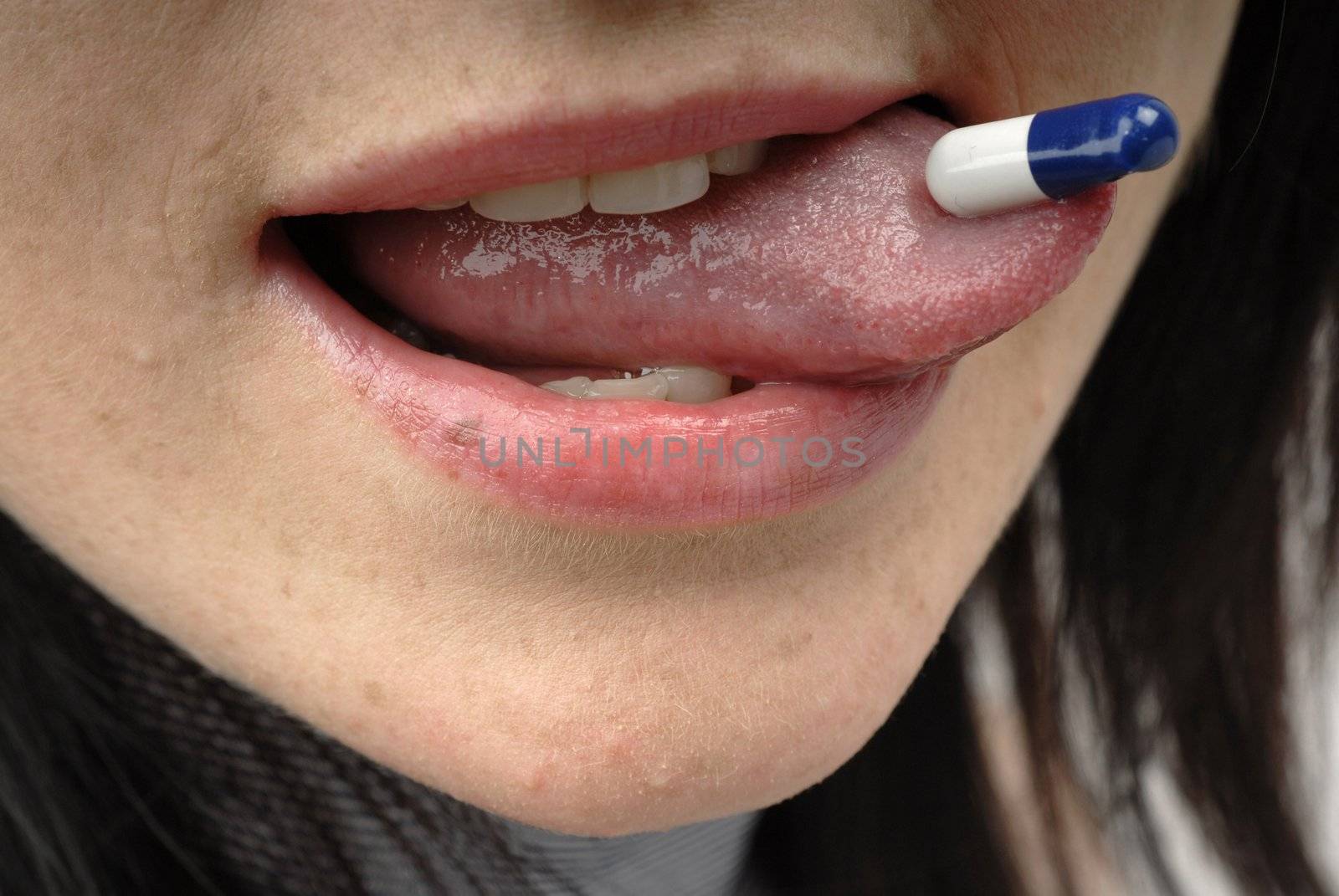 Young woman with pill on her tongue