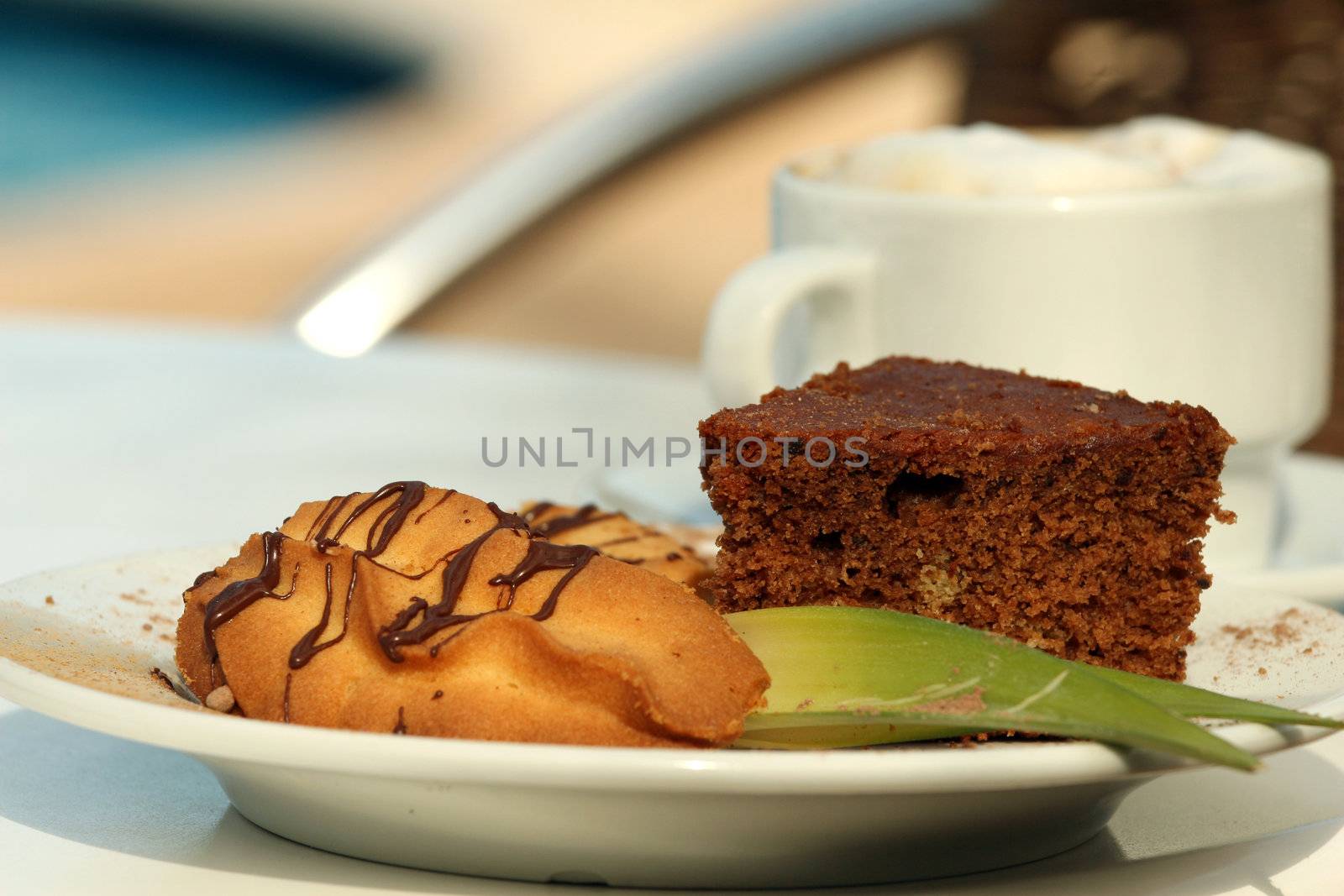 Tasty cookies with a cup cappuccino by the pool