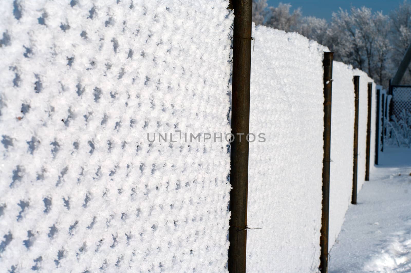 Metal wire mesh fence covered with snow.