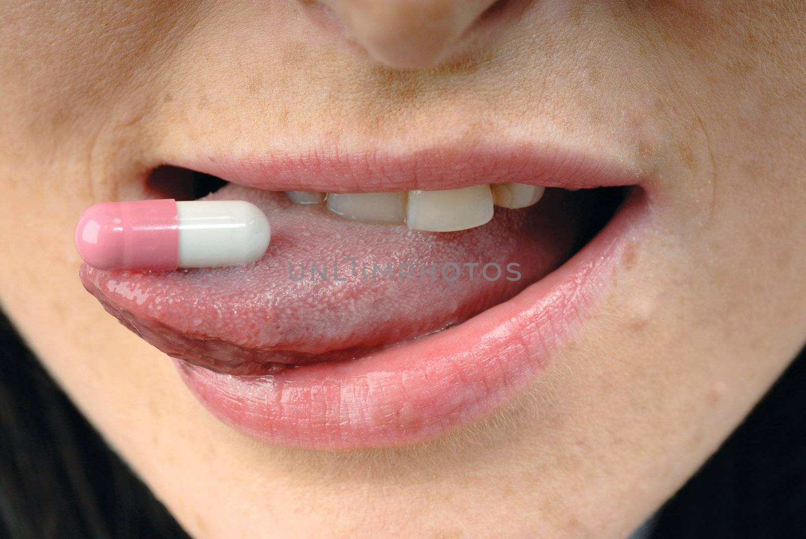 Young woman's face with pink pill