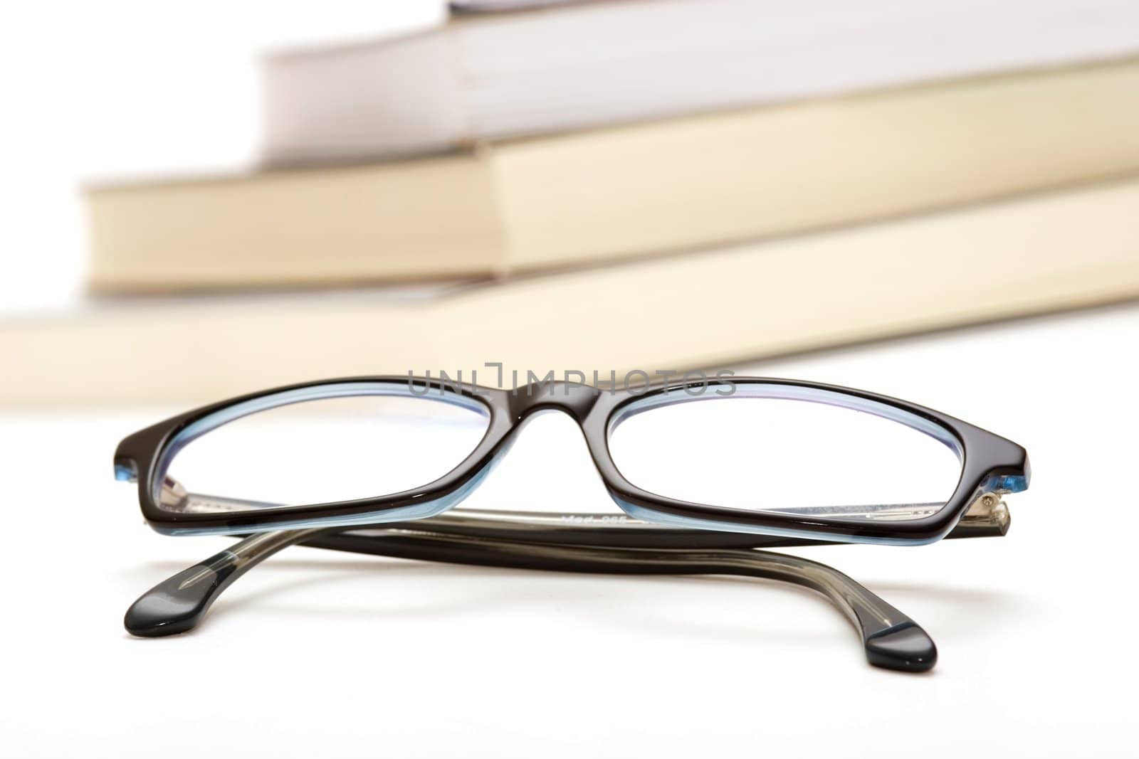 Books and reading glasses on white background