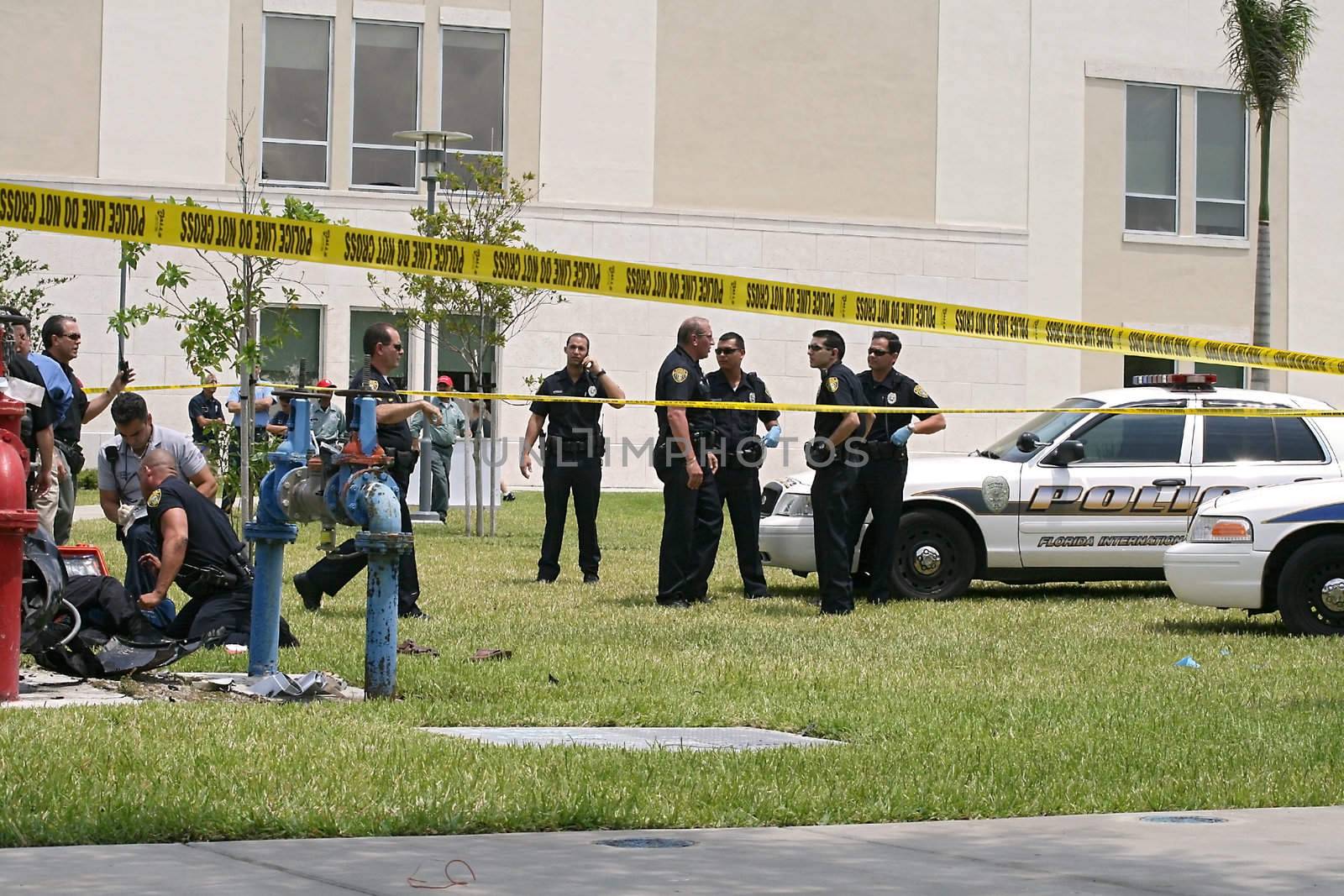 Police and paramedics work at the scene of a car crash resulting from a chase on a university campus.