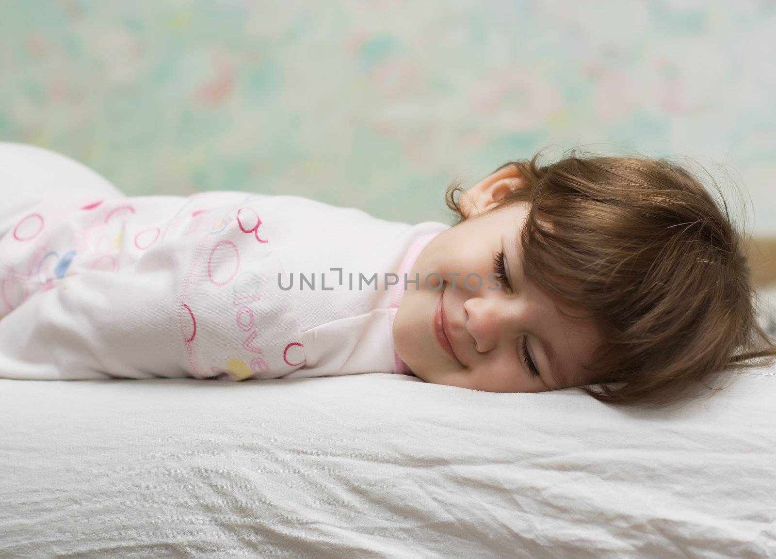 little girl with closed eyes, lying in bed and smile