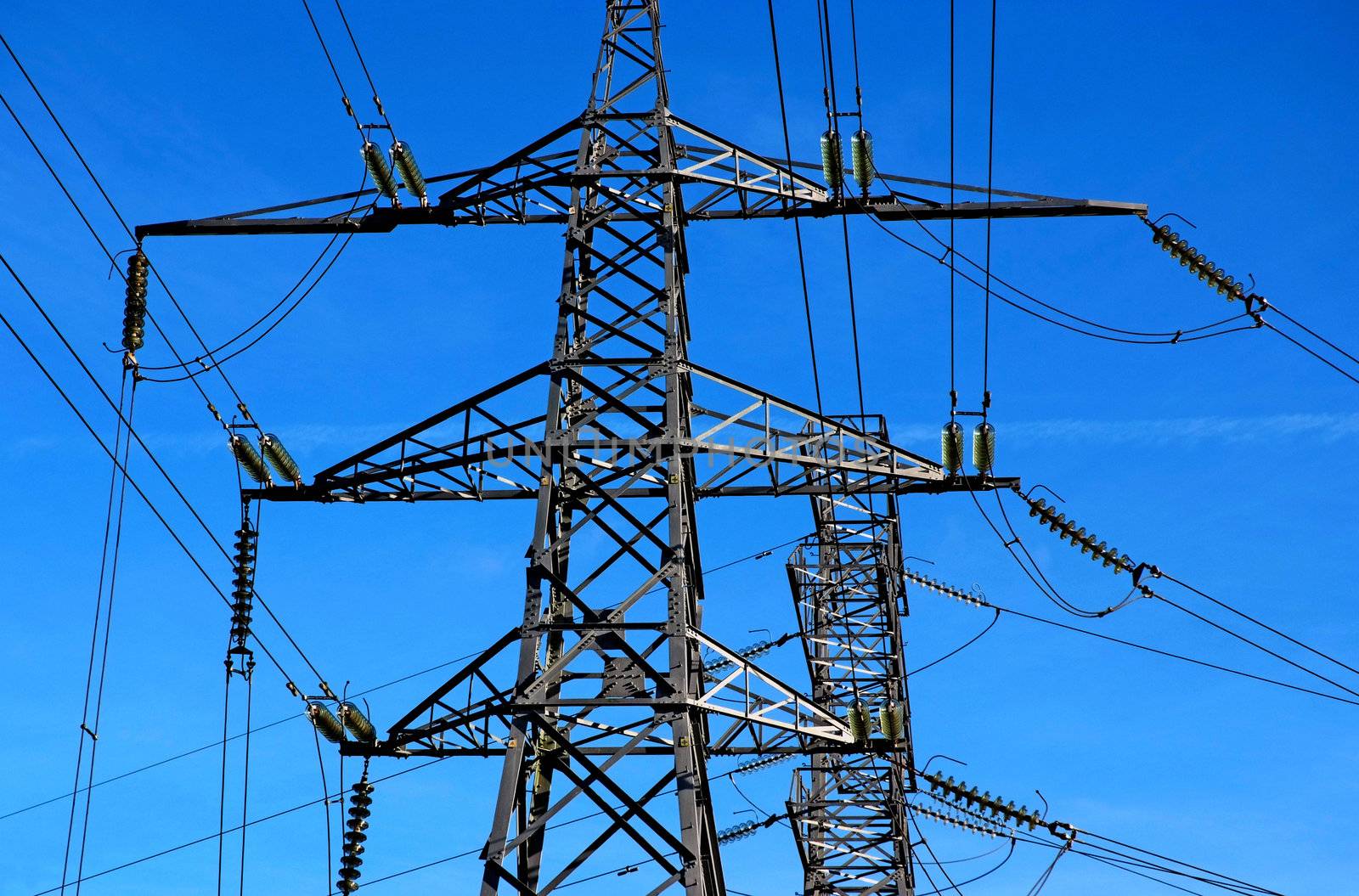 Two electricity pylons with a blue sky background