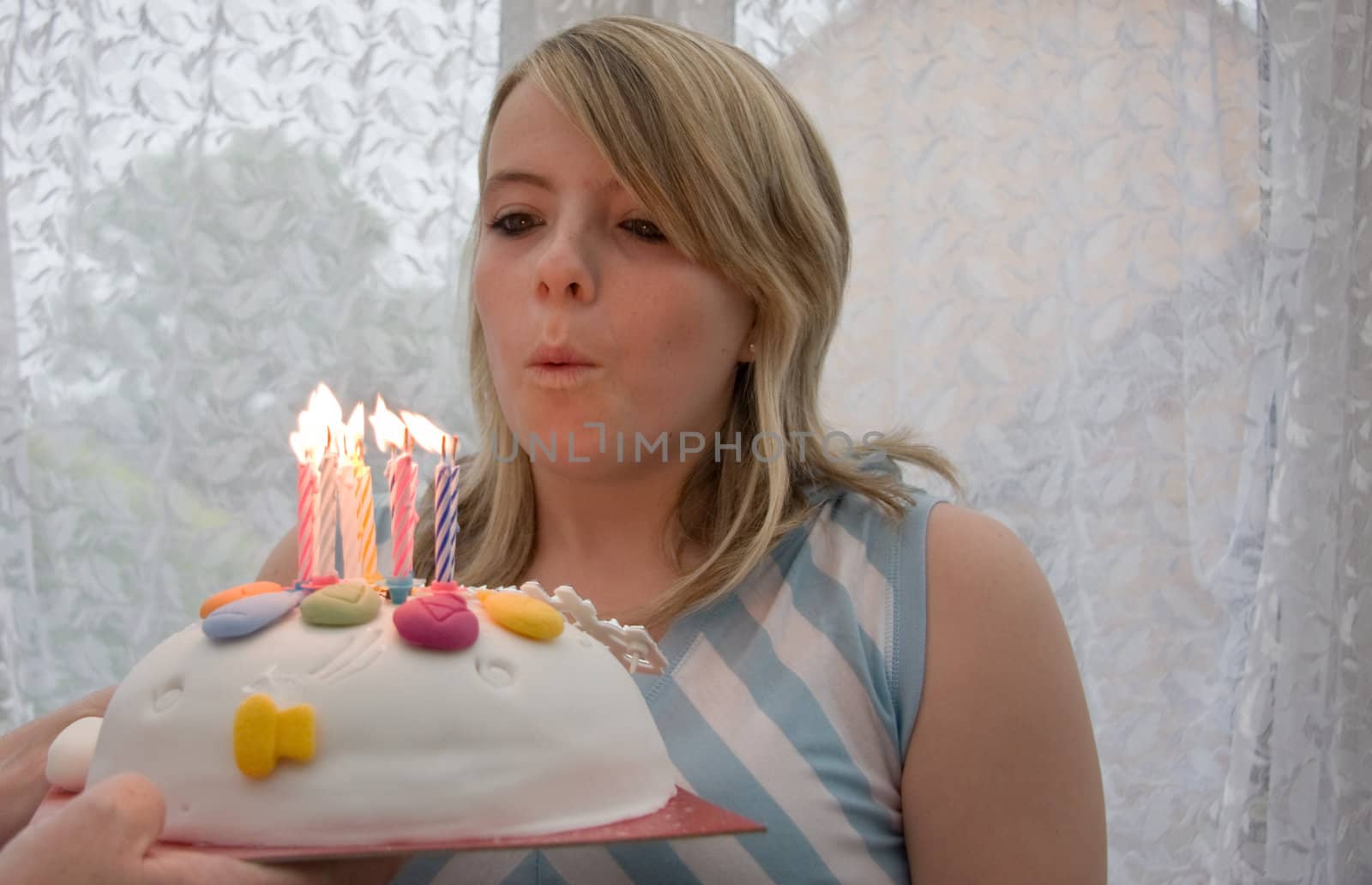 bpretty teenage girl blowing out the candles on her birthday cake.