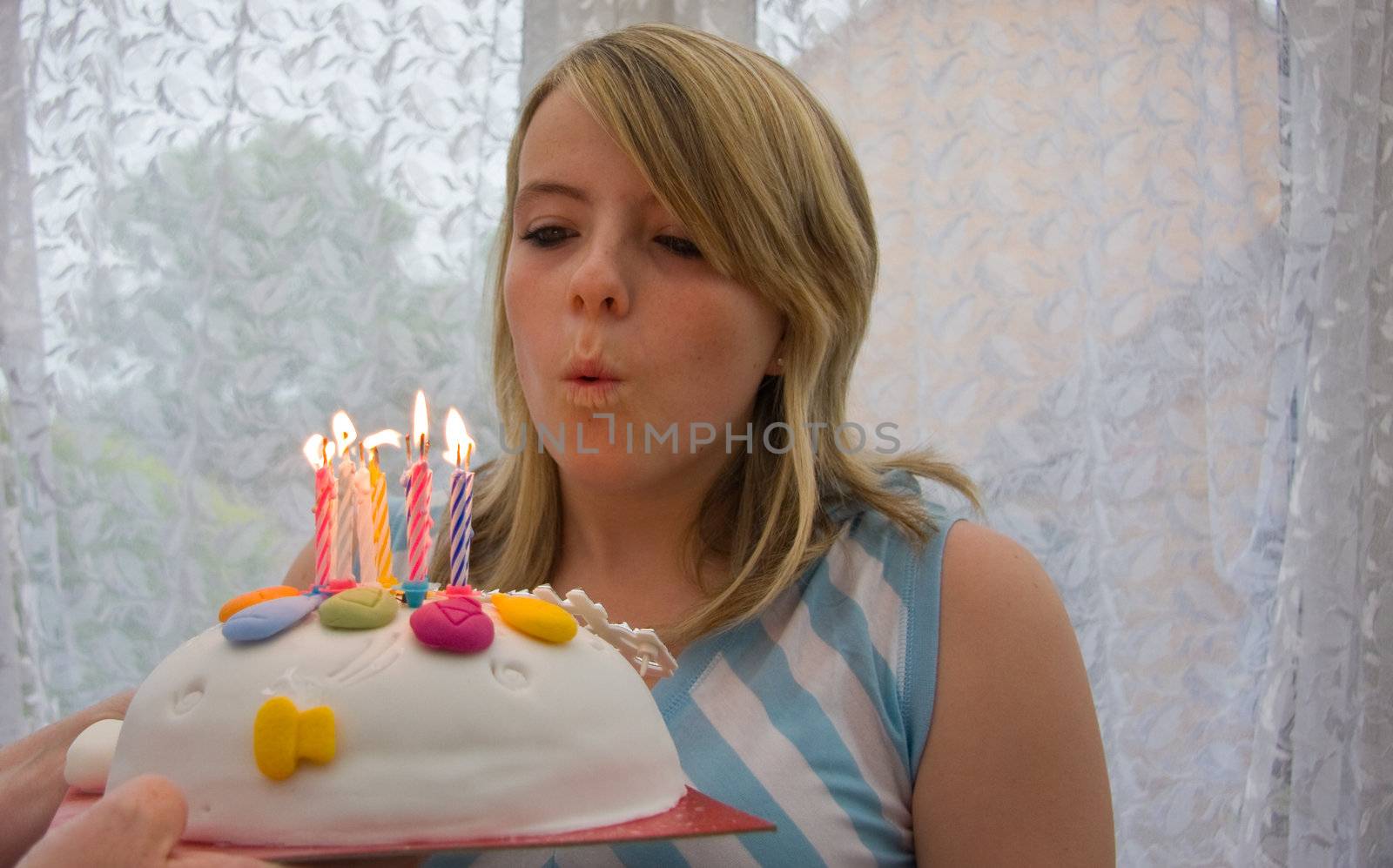 Pretty girl blowing out the candles on her birthday cake.
