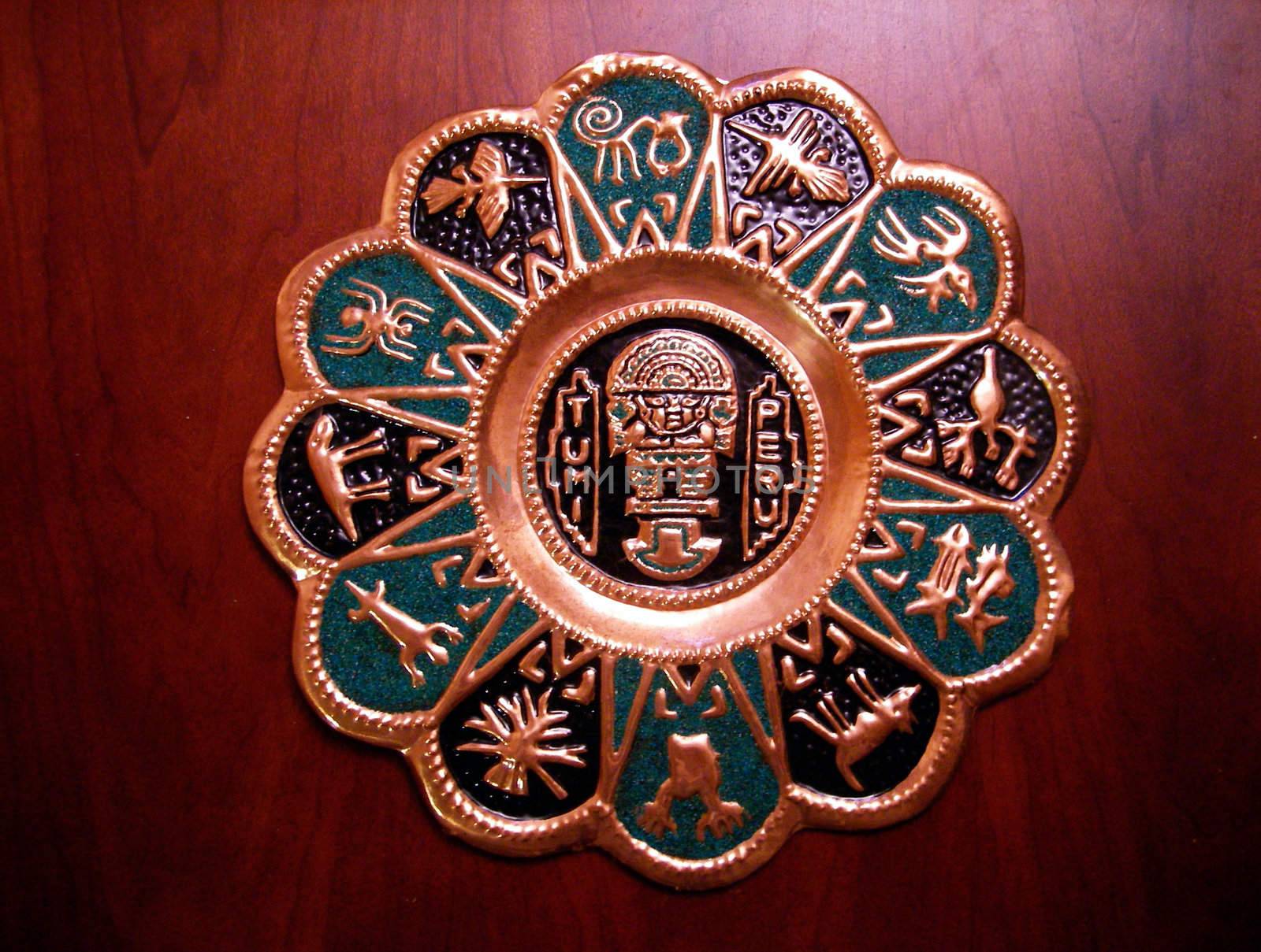 A Tumi is a sacrificial knife. In Peru, it is considered good luck to have one hanging on your wall. This is a stamped plaque sold by Peruvian vendors and includes a representation of a tumi in the center surrounded by the Peruvian zodiac on the outside.