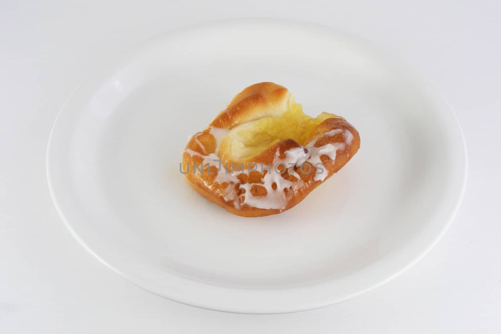 A pineapple danish roll with sugar icing.