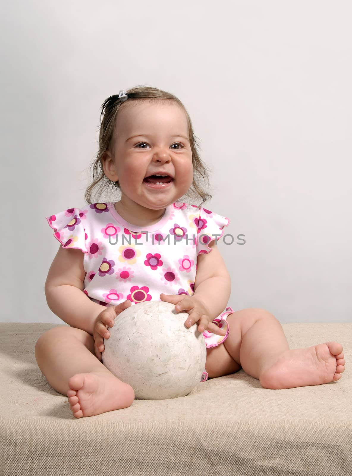 Laughing cute baby with white ball isolated on white background
