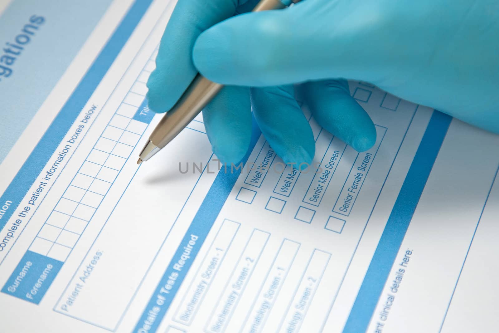 Health professional with blue gloves, completing pathology blood test request form.