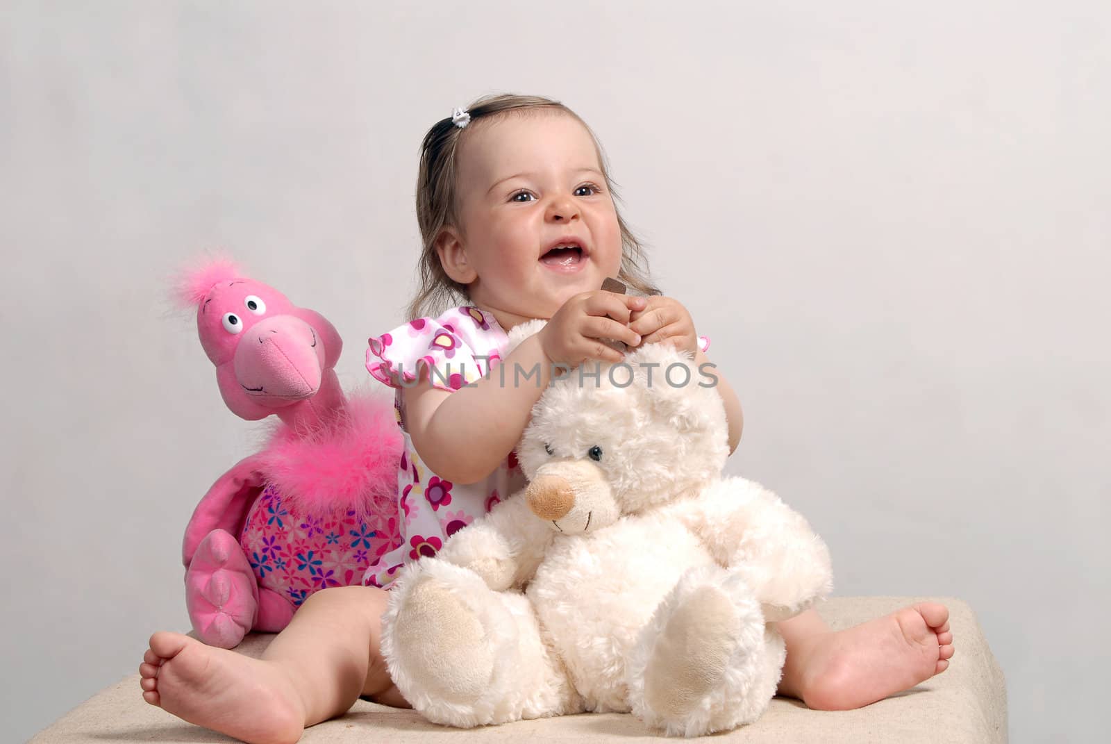 Laughing cute baby with teddy bear and rose flamingo isolated on white background
