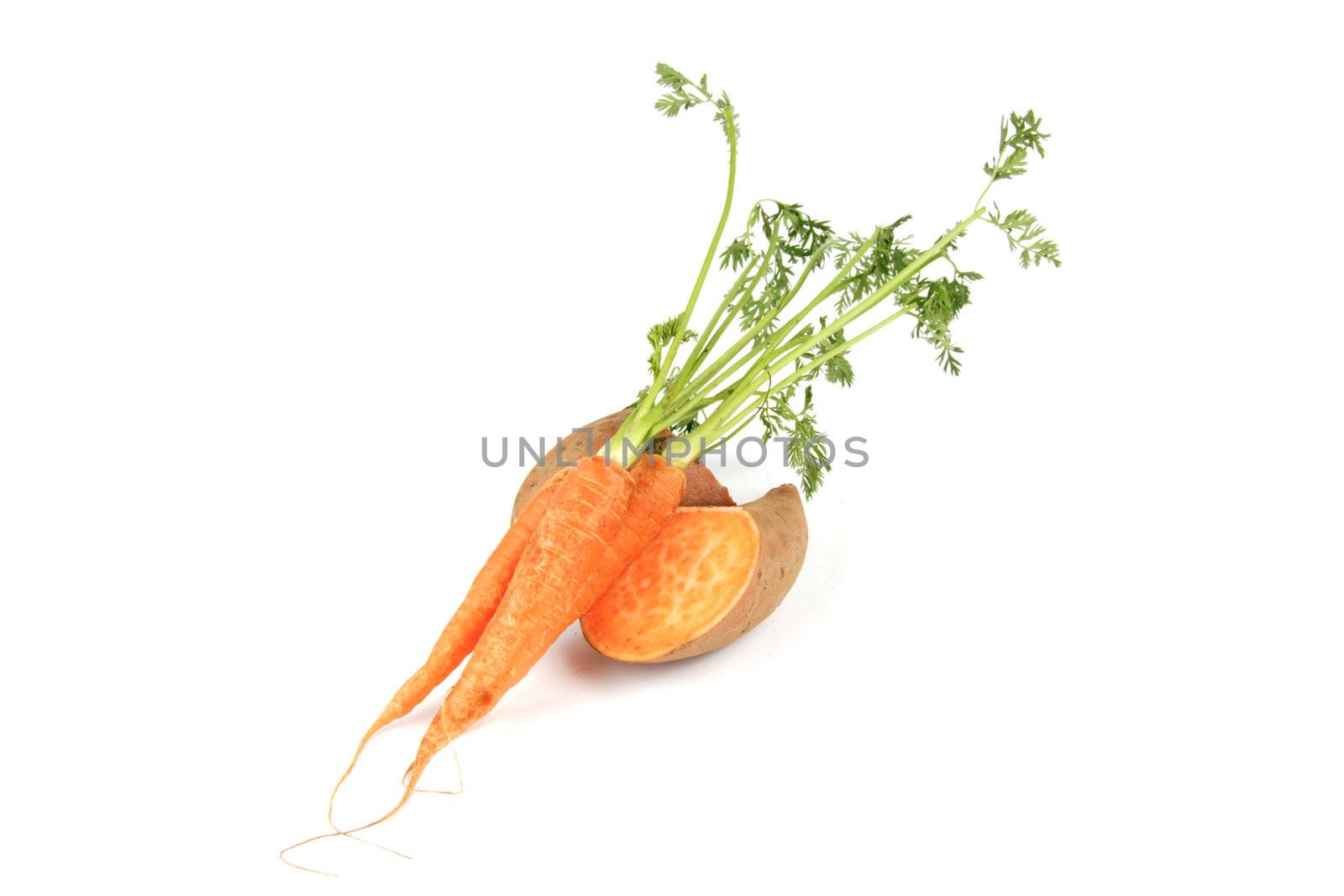 Sweet Potato cut in half with a bunch of raw carrots on a reflective white background