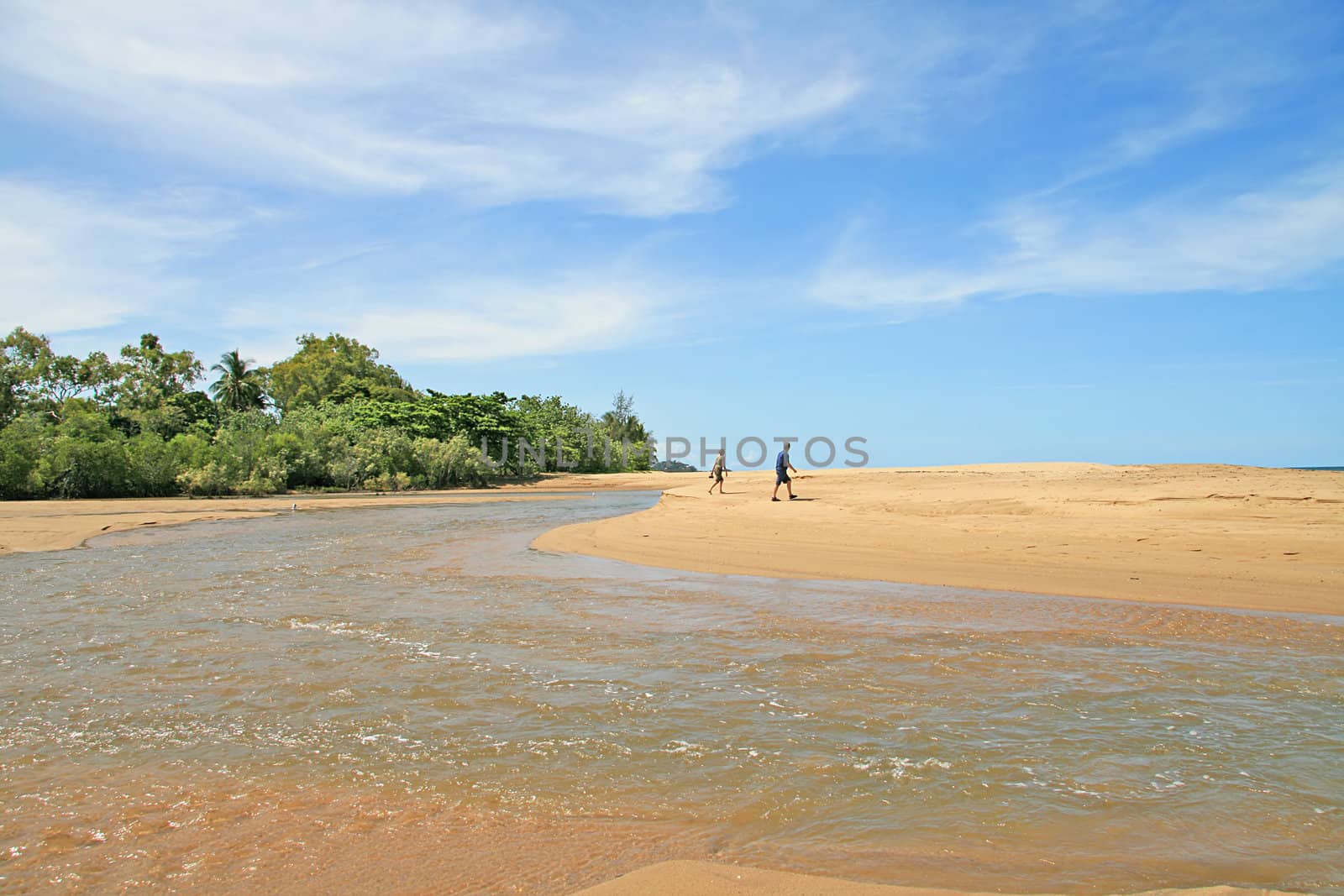 Couple walking across the sand of Machans Beach