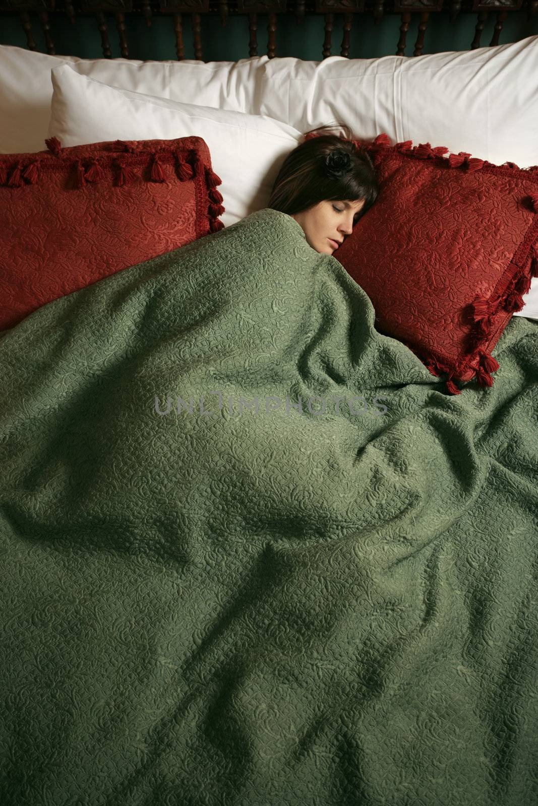 Photo of a beautiful female sleeping alone in a large bed.