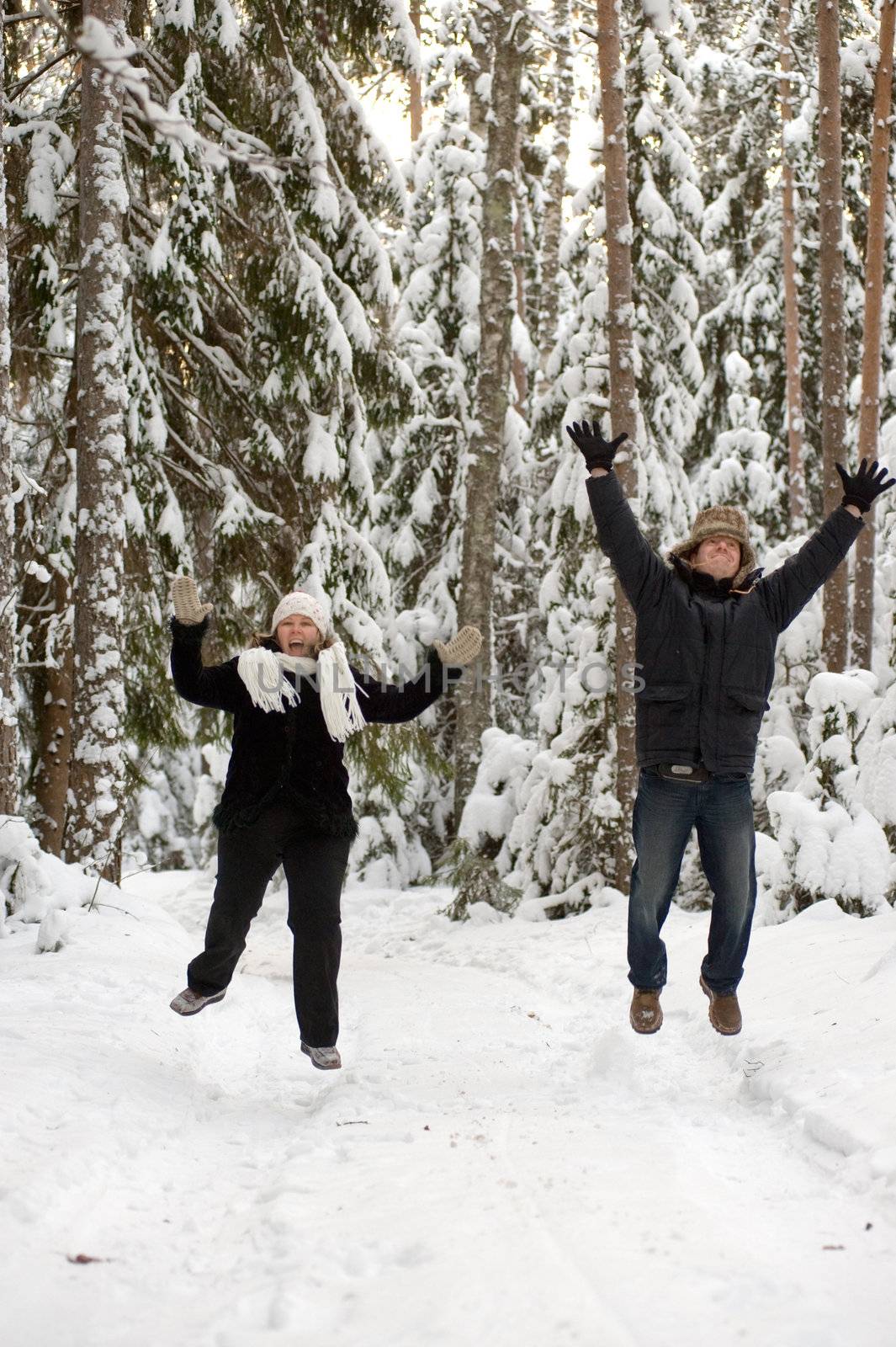 Happy middle-aged couple jumping on a winter day 
