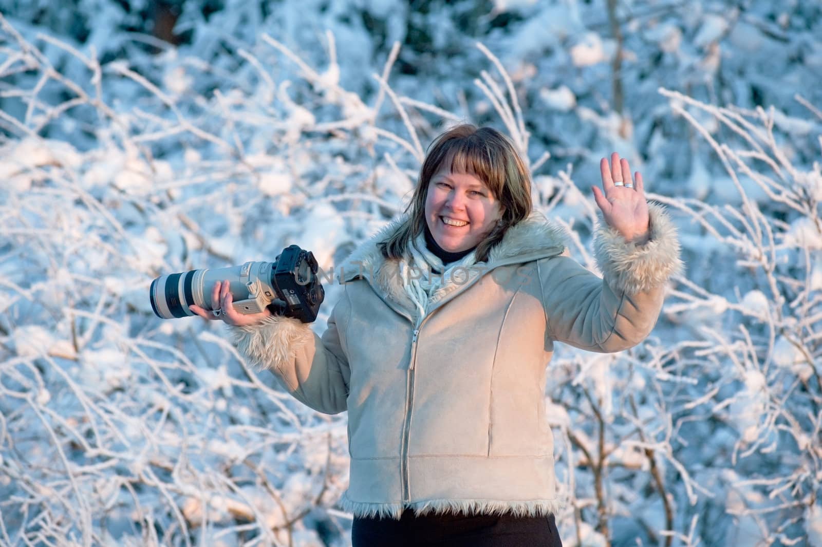 Happy middle-aged women photographer on winters day in forest.