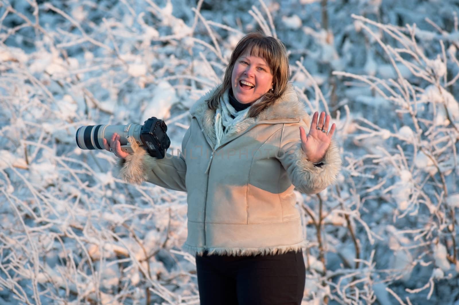 Happy middle-aged women photographer on winters day in forest.