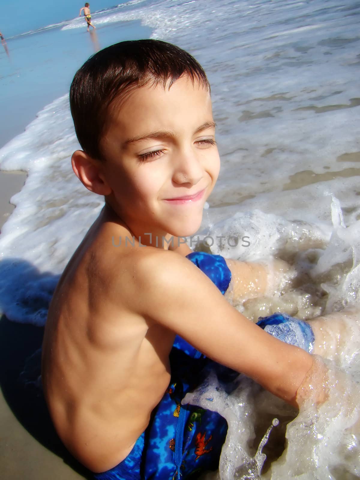 a young boy sits on the shore at daytona beach