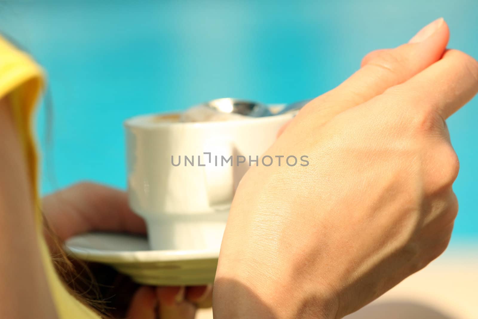 Woman drinking a cup cappuccino by the pool