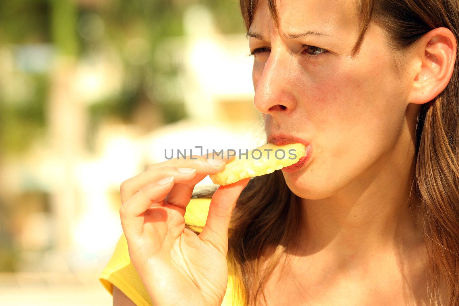Girl eating fresh and tasty ananas by the pool