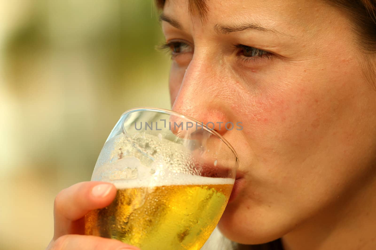 Girl drinking glass beer by the pool