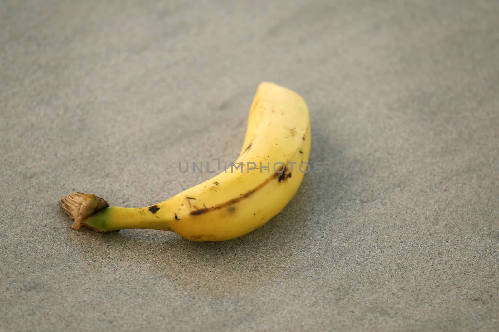 single banana lying on the sand beach