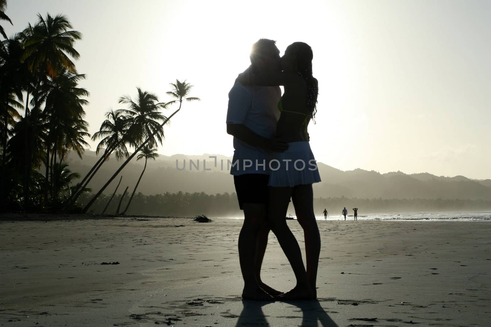 natural couple kissing at the beach by sunset