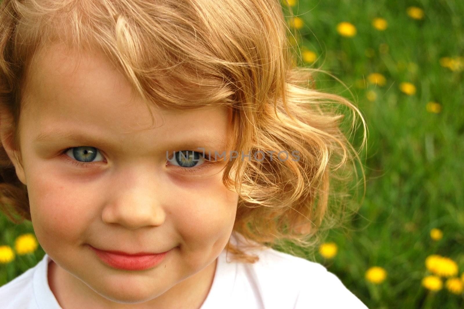 Portrait of small pretty girl with curly hair and blue eyes