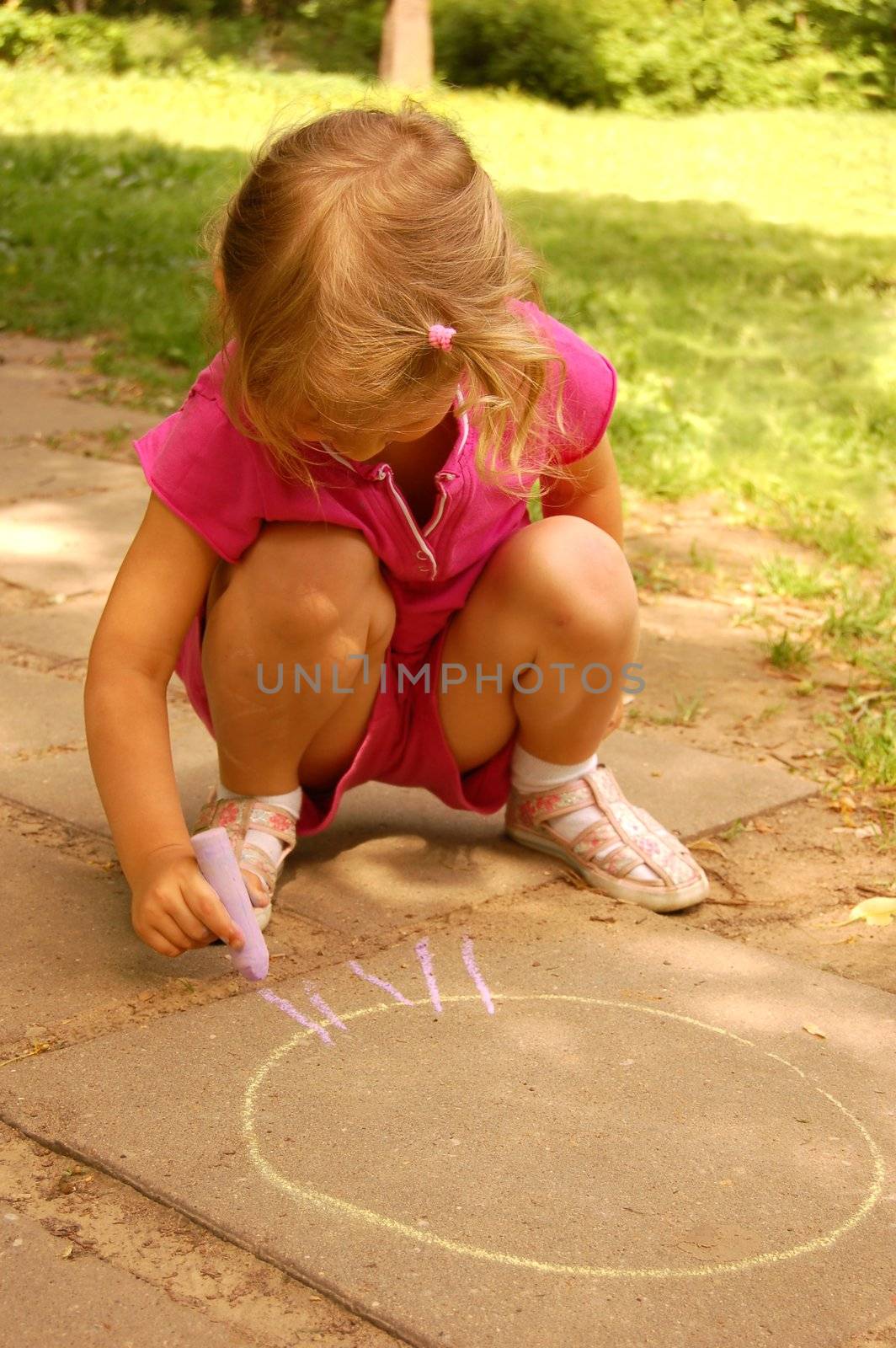 little girl drawing sun with chalk