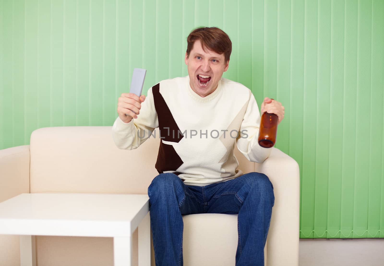 Football fan sitting at home on the couch with a TV