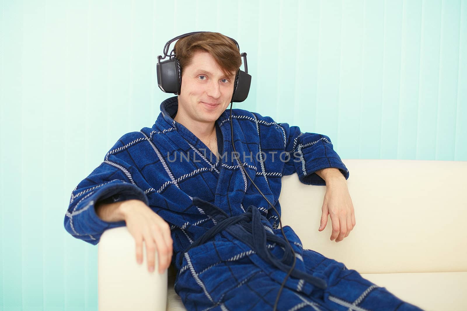 Man in big ear-phones sits on sofa by pzaxe