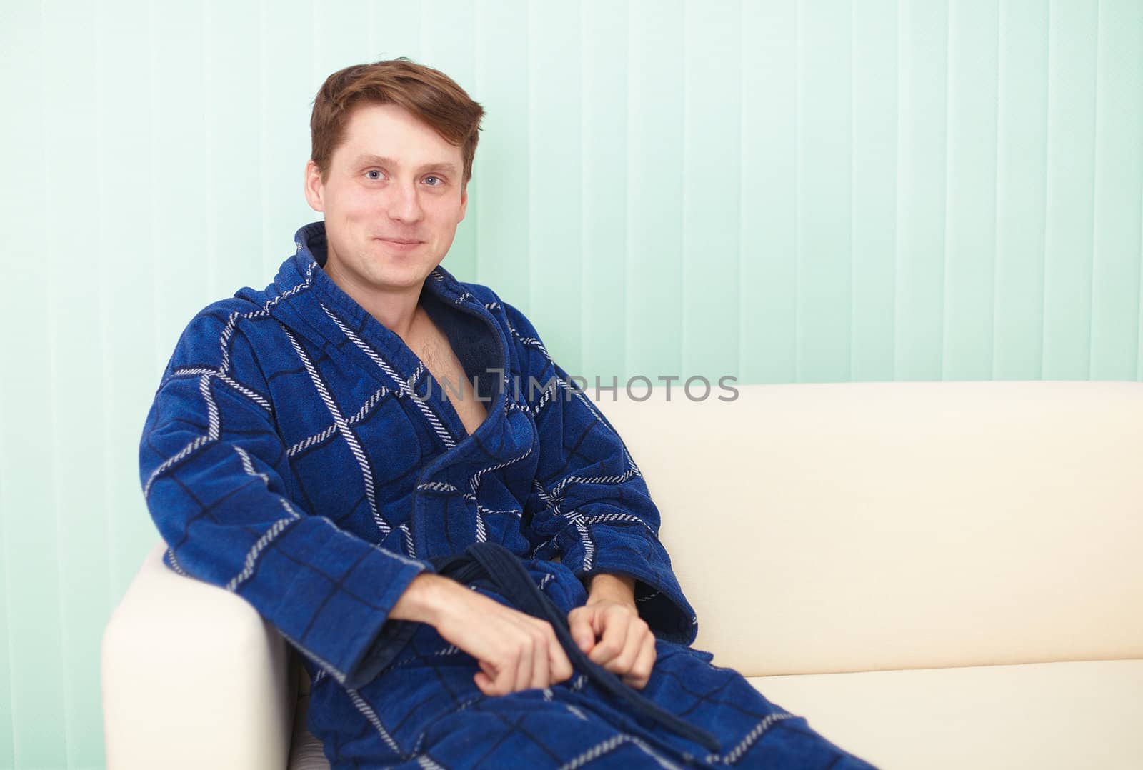 The guy sitting on a couch in a blue gown