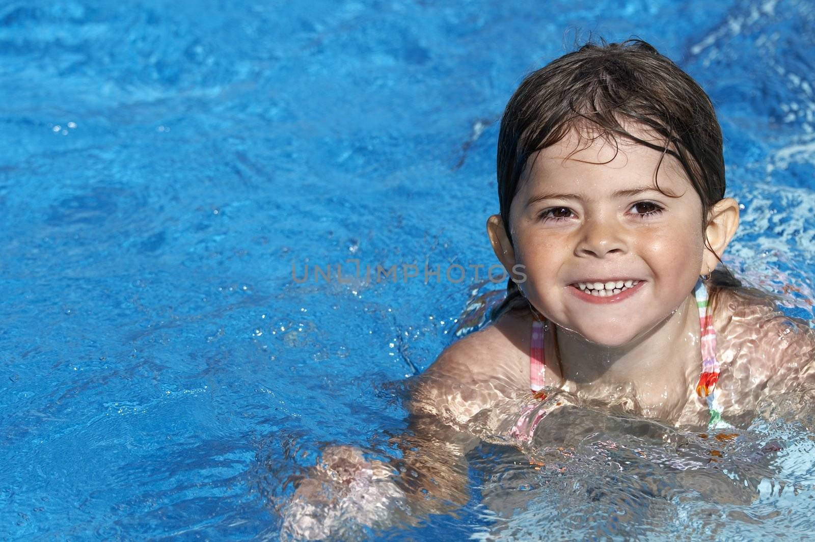 a cute little girl in pool water during the summer
