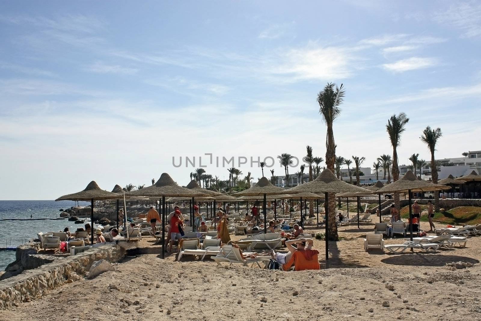 Egypt, on a beach people sunbathe. In the blue sky - small clouds.