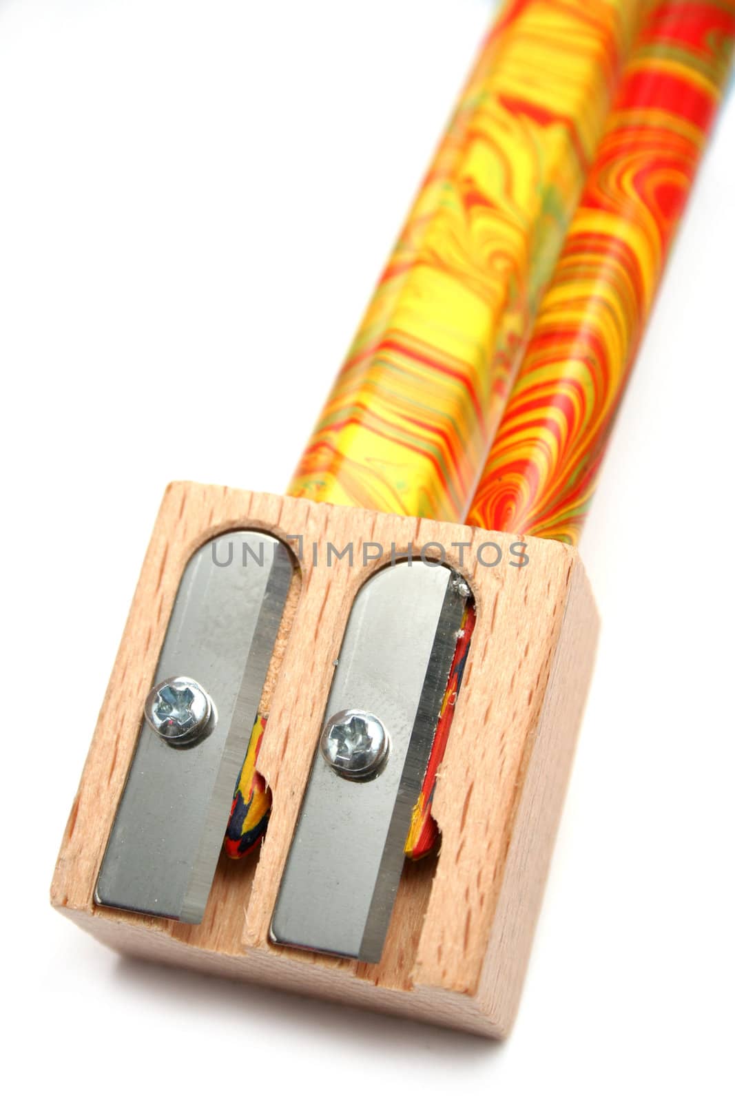 Two multi-coloured pencils inside of a wooden sharpener for pencils 