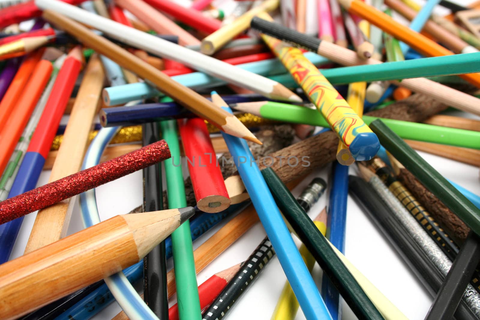 Heap of multi-colour pencils from a tree and plastic on a white table