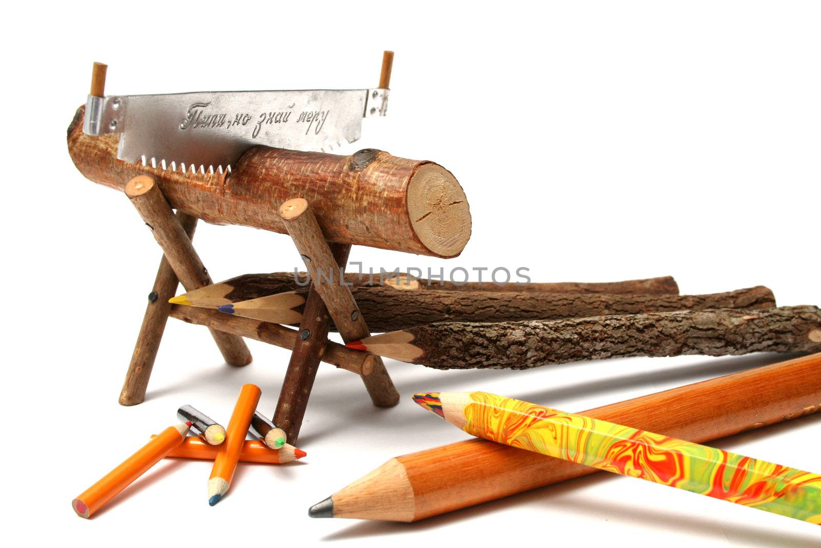 Pencils from natural wood of various type near to a saw by parrus