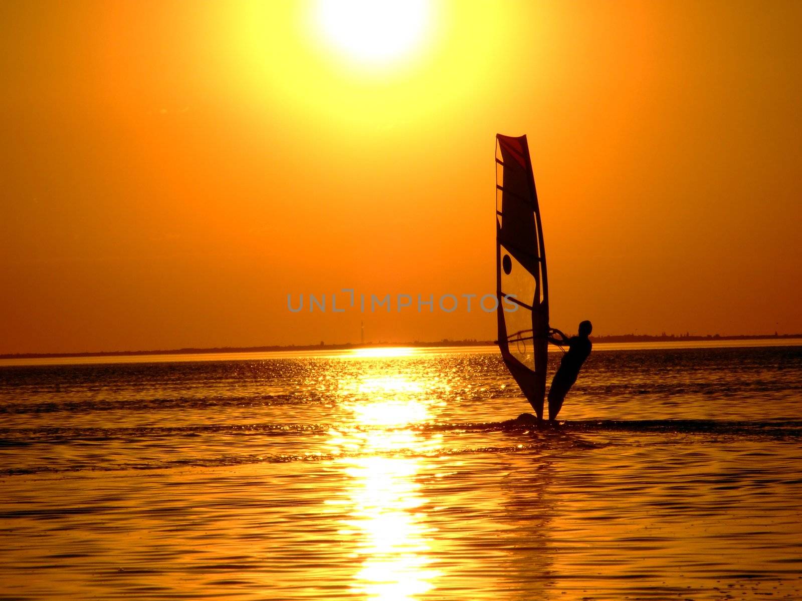 Silhouette of a windsurfer on waves of a gulf on a sunset by acidgrey