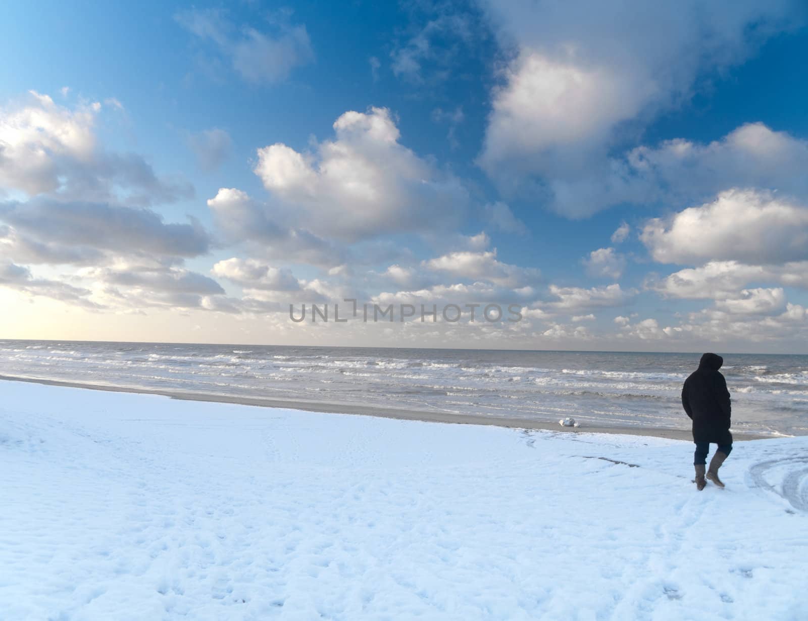 Man walking in snowy beach along the North sea in France