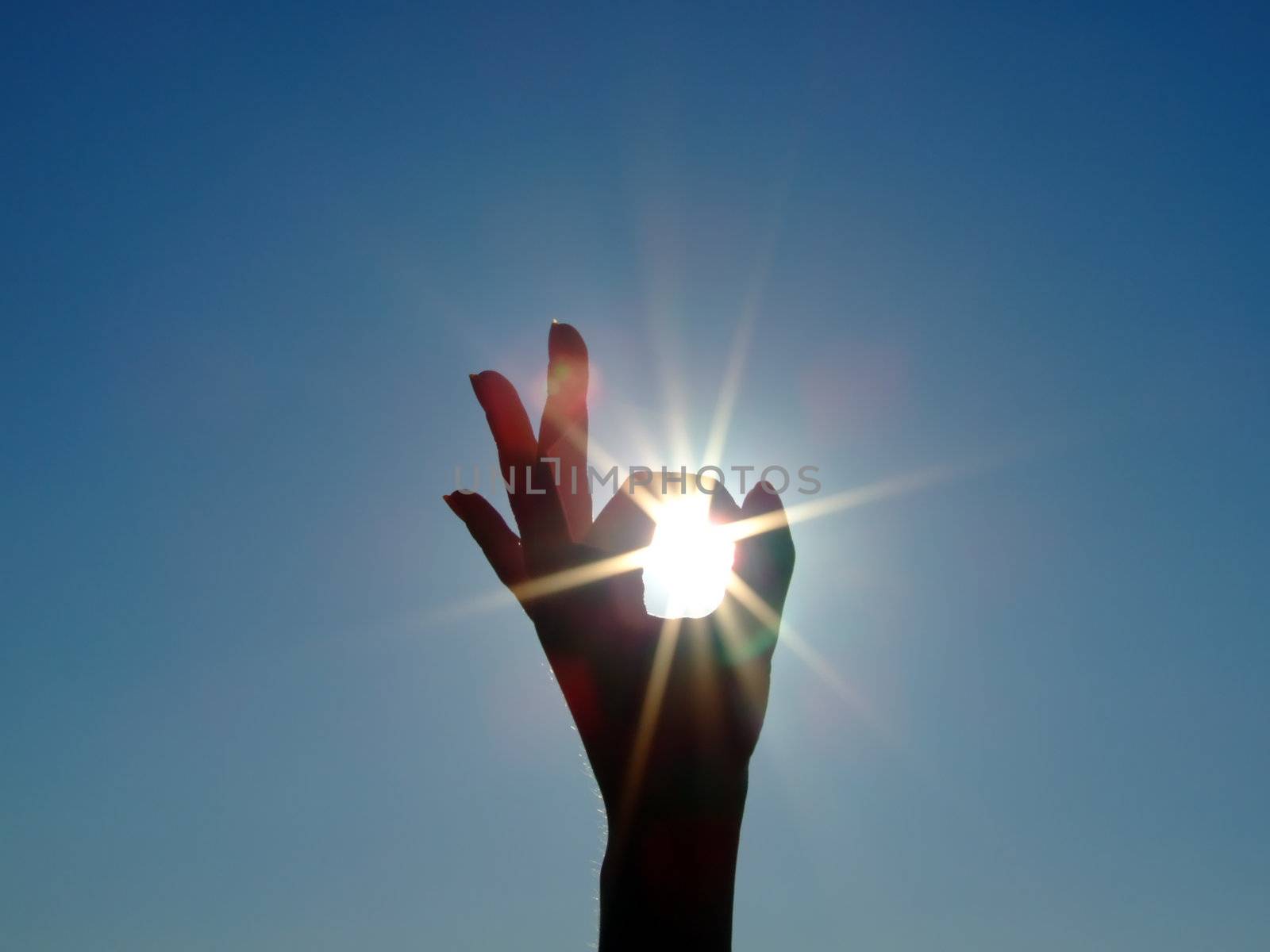 Silhouette of a female hand, the blue sky and the bright sun by acidgrey